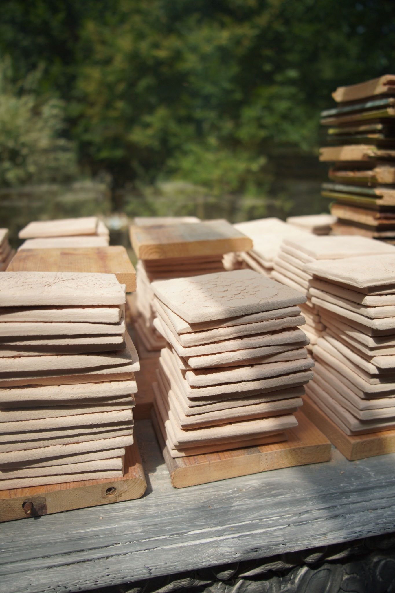 Dried Flemish Relief tiles stacked in prepared atelier batches.